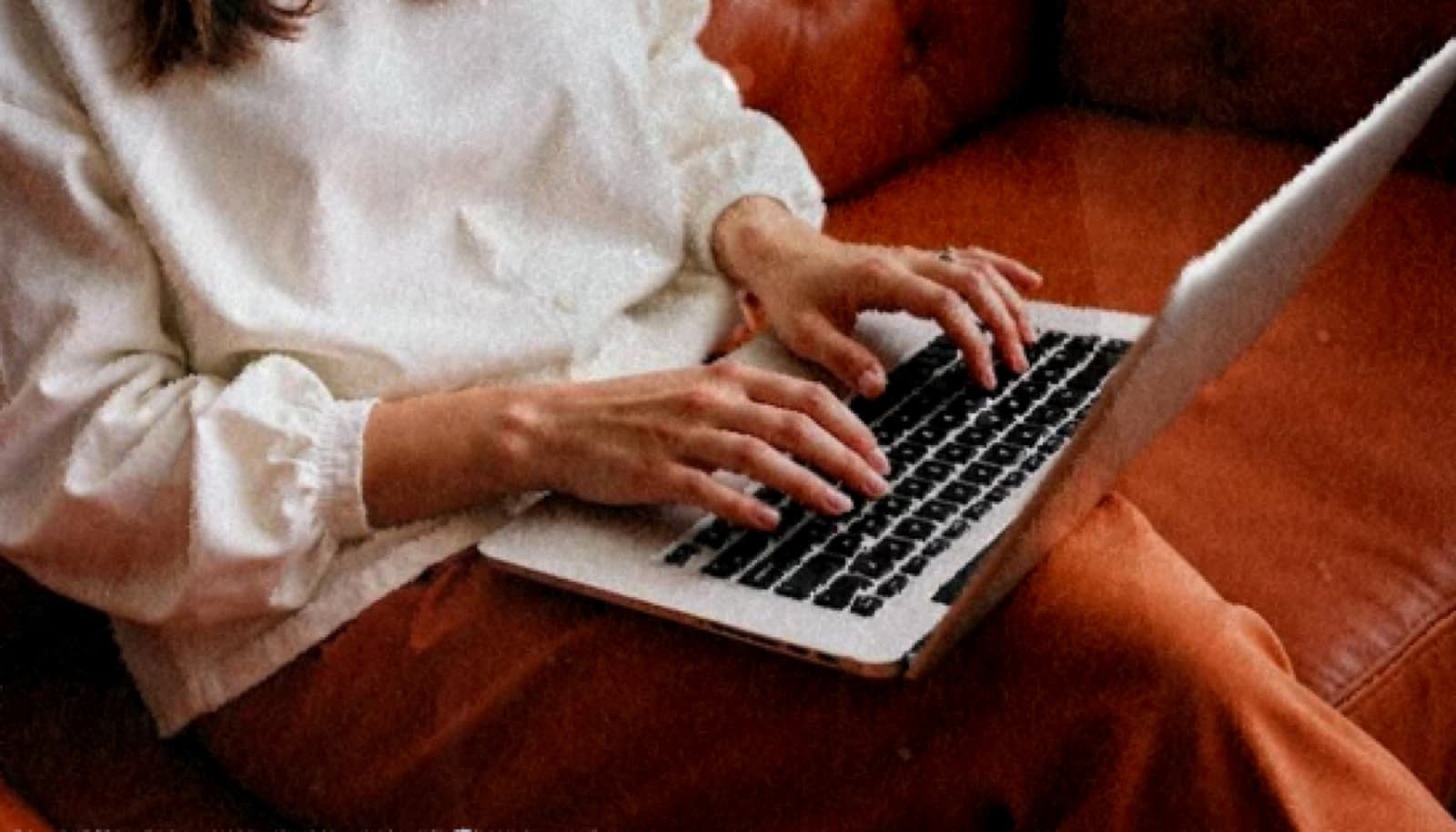 A founder typing on a laptop from a terracotta leather sofa, rendered in Kinect's painterly texture